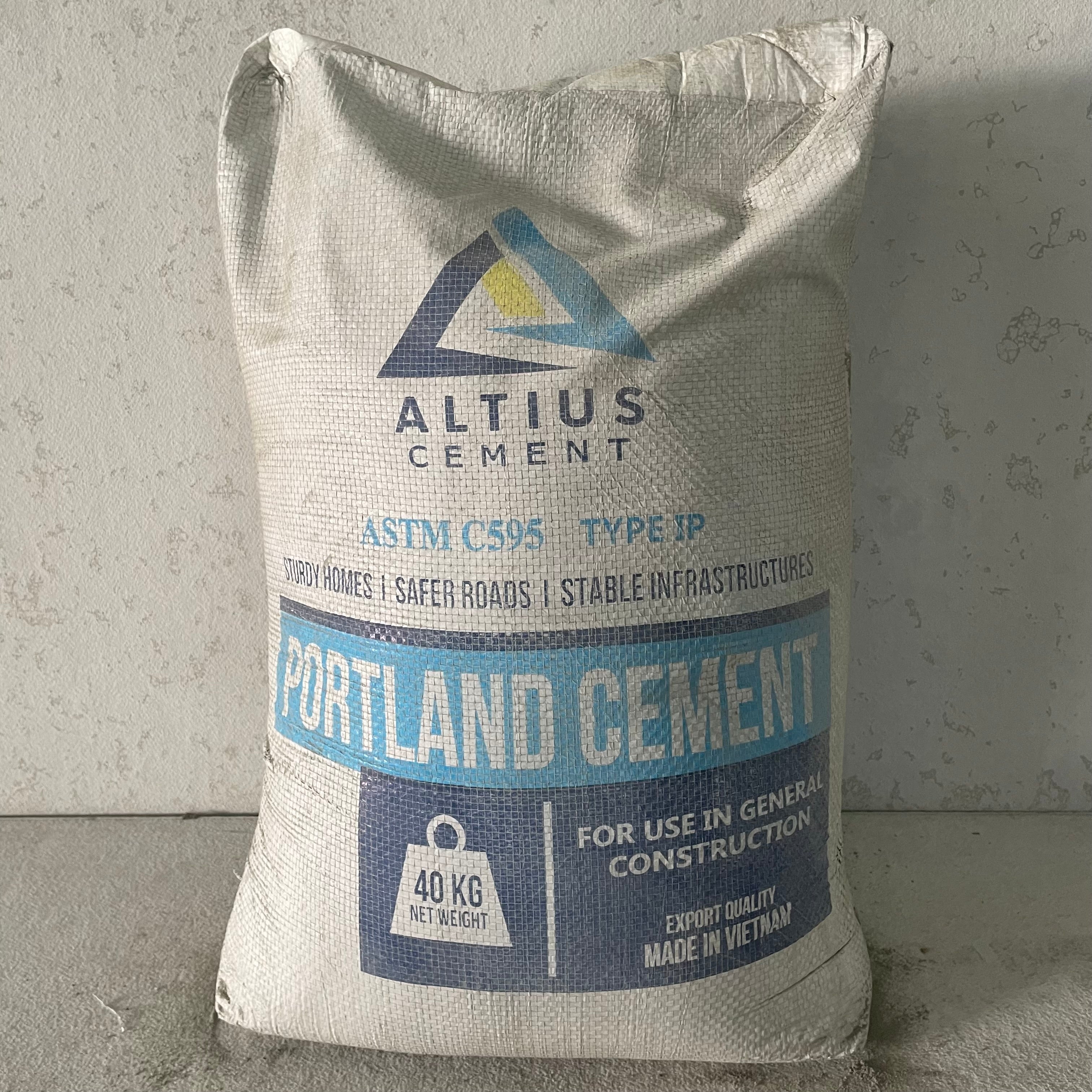 A 40kg bag of ASTM C150 type I cement from Portland Cement Company, with product details and branding on the label.